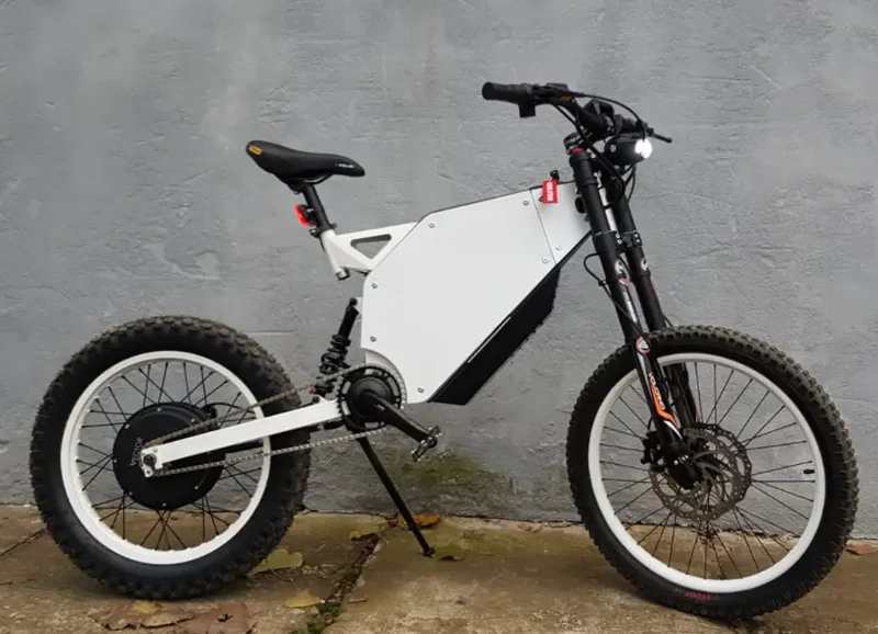 alaria X3 Pro 5kw Electric Bike transitioning from urban street to a light off-road trail in Europe.